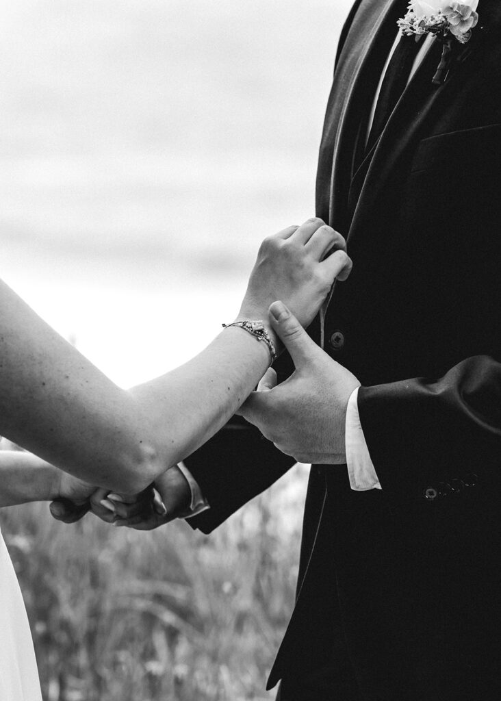 a detail black and white photo of the bride and groom holding hands