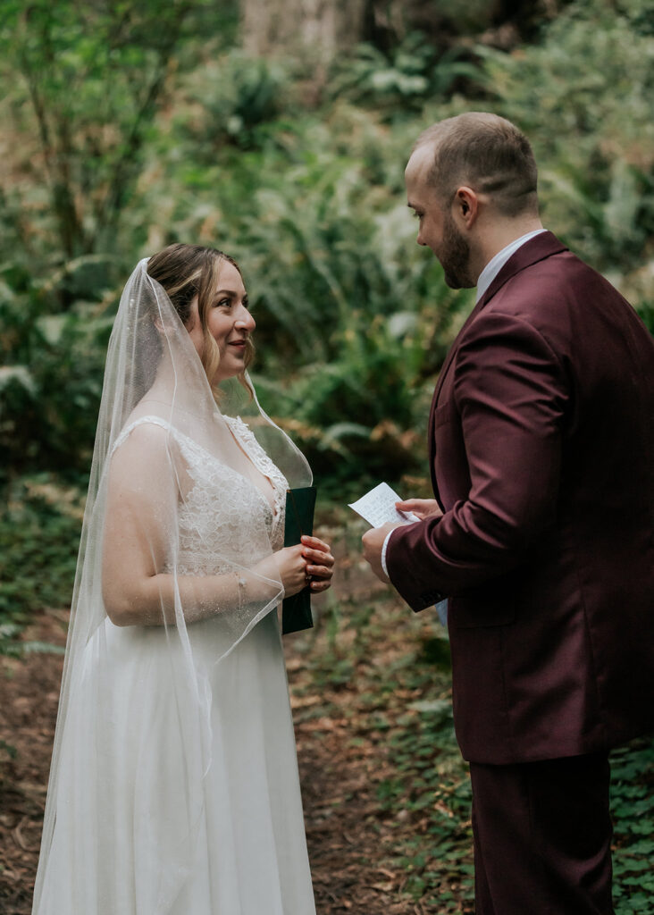 Our bride gazes lovingly at her groom as he reads his vows during their forest wedding