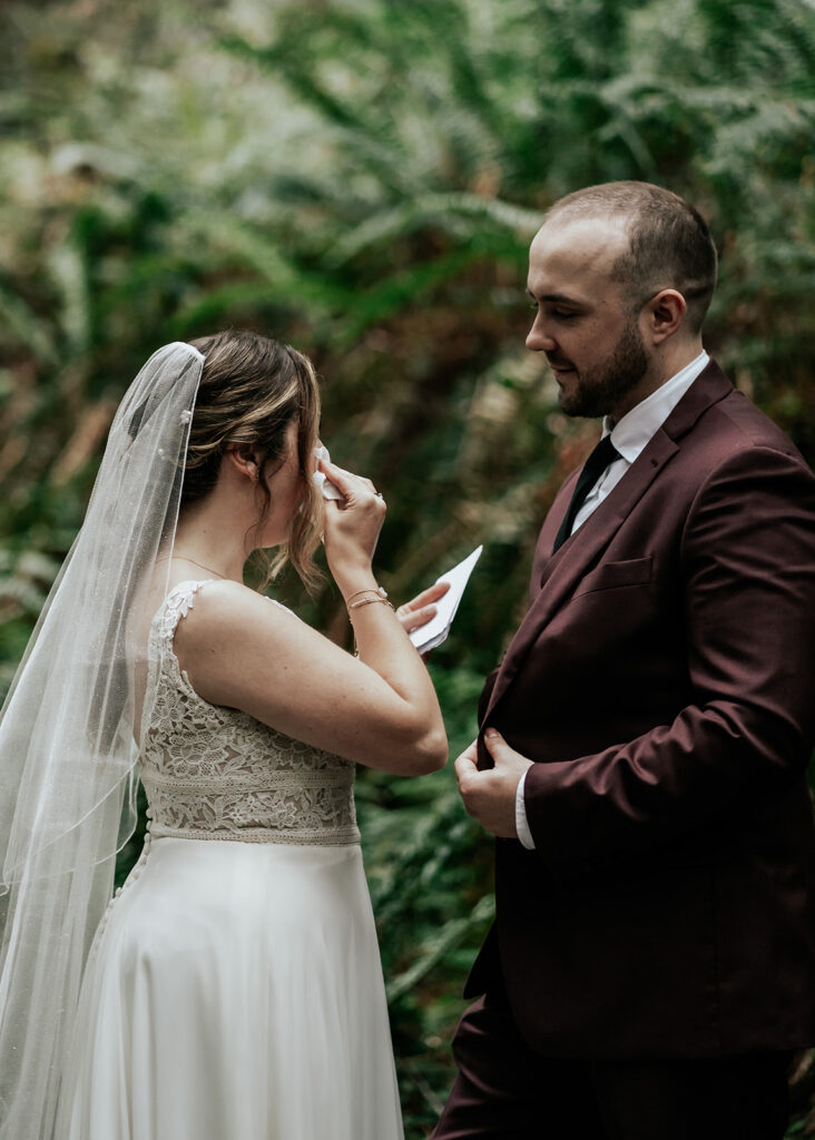 A bride wipes her tears as she reads her vows to her groom during their forest wedding