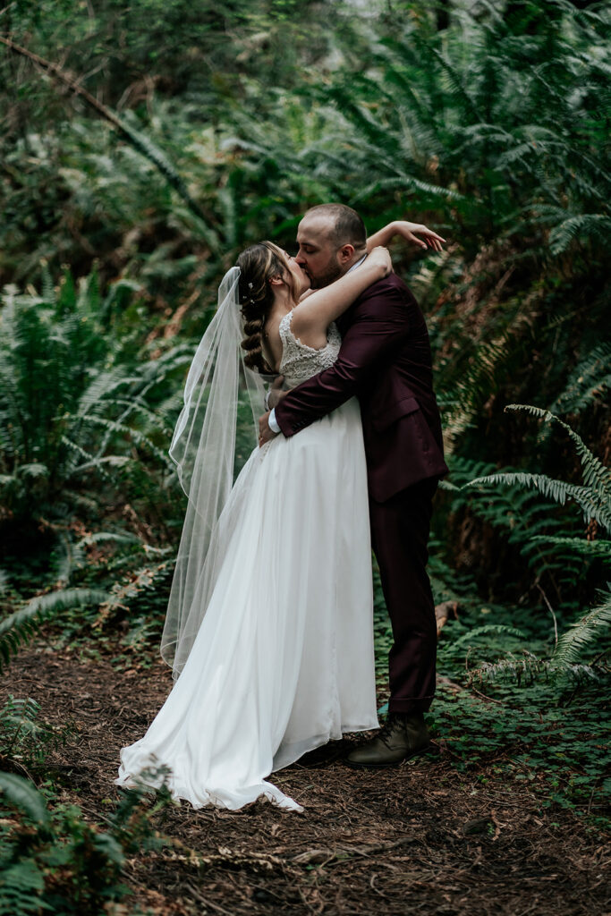 a bride and groom exchange their first kiss during their forest wedding