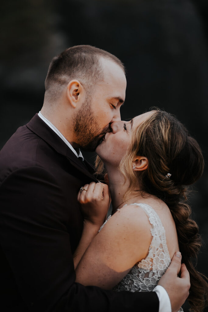 a bride and groom lit by lanterns embrace and kiss on their wedding day