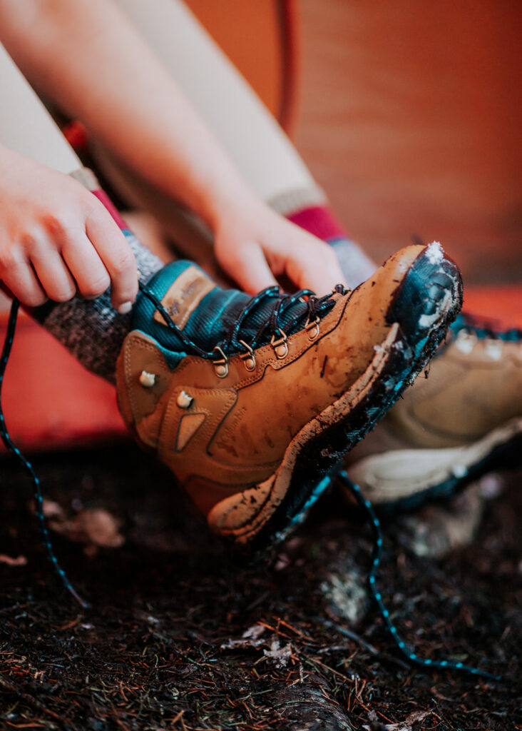 a close up shot of a bride lacing up her hiking boots for her backpacking wedding