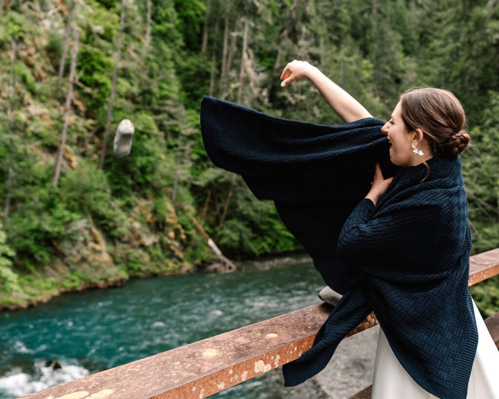 celebrating their backpacking elopement, a bride throws a heavy rock off the bridge