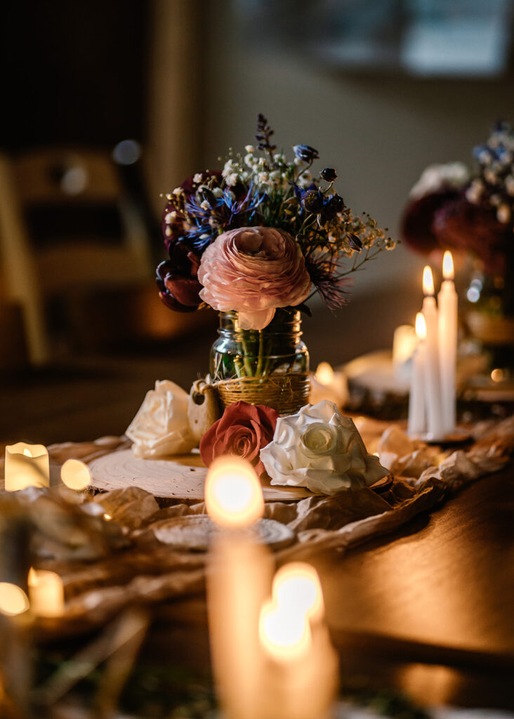 detail images from the reception of this backpacking wedding. a table is decorated with local blooms, surrounded by lit candles and soft fabric