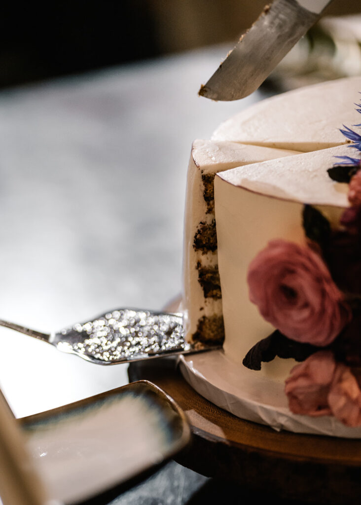 a close up of cutting a wedding cake 