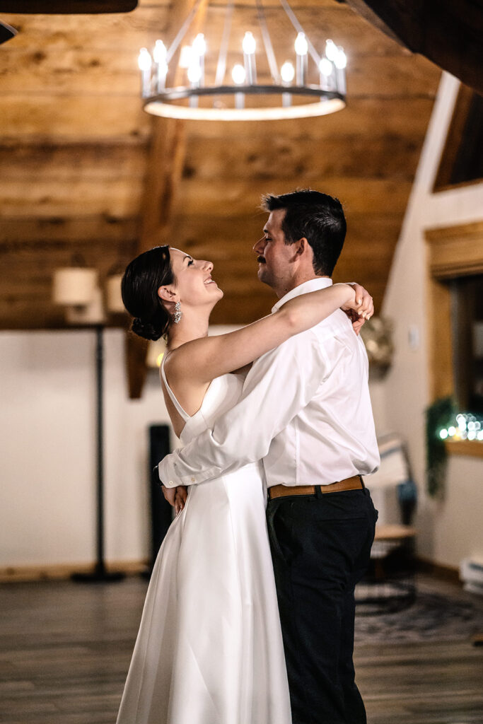 a bride and groom dance in the living room  of their cabin to end their backpacking wedding