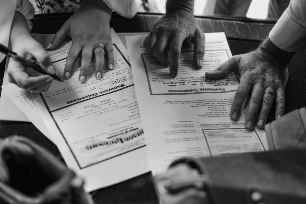 after their elopement ceremony, a bride and groom sign their marriage license in the back of a car 