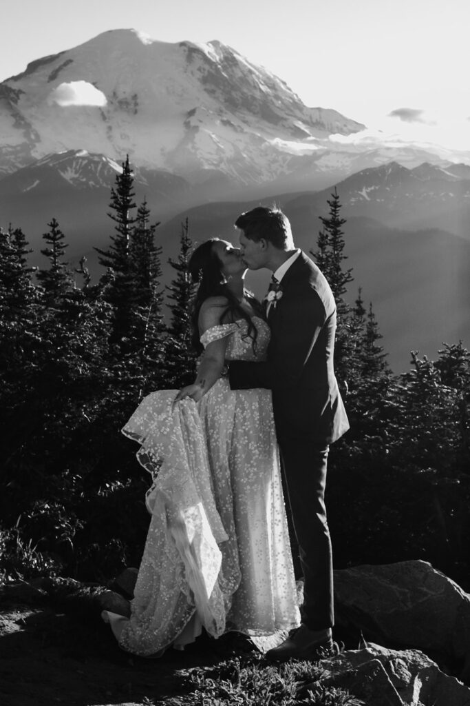 a black and white photo of a bride and groom kissing in front of mount Rainier during their elopement ceremony