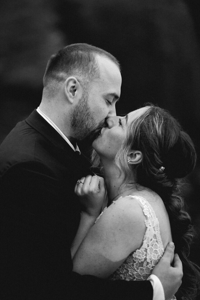 a black and white photo of a bride and groom sharing their first kiss after their elopement ceremony