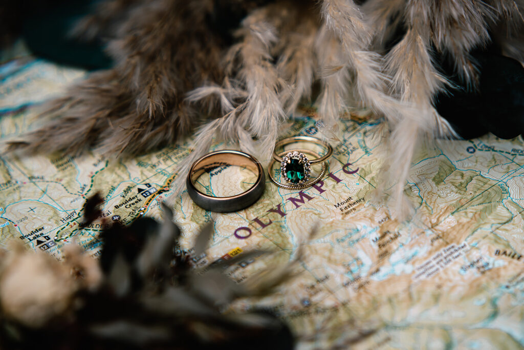 a shot of elopement ceremony details in soft light. wedding rings and a dried bouquet are placed on a brightly covered map 