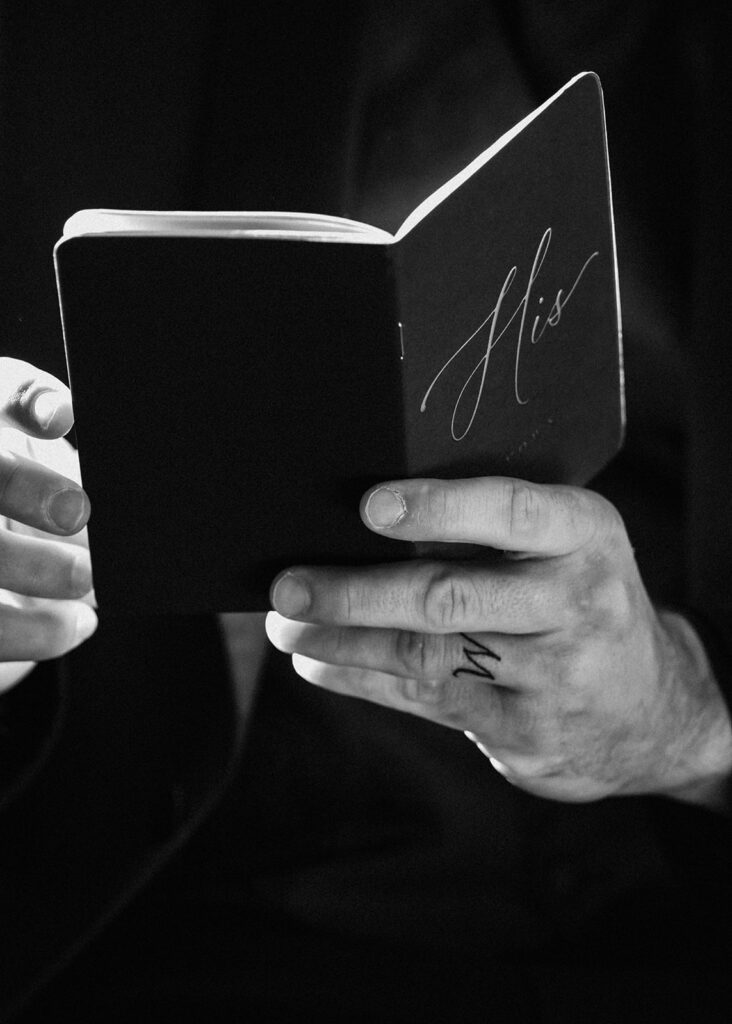 a black and white photo of a grooms vow book. He holds it as he reads from it during his elopement ceremony 