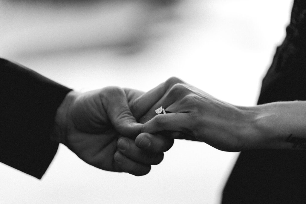 a black and white shot of a groom placing a ring on his brides finger during their pacific northwest elopement