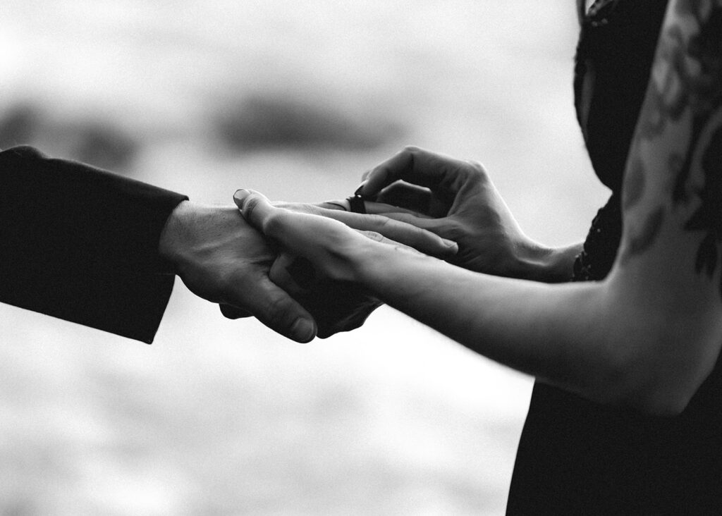 a black and white shot of a bride placing a ring on her grooms finger during their pacific northwest elopement