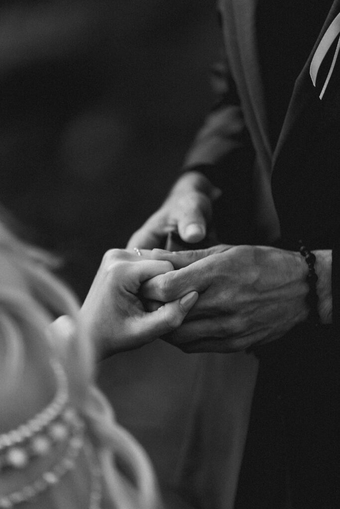 a close up black and white image of a bride and groom holding hands. we see that he has just placed a wedding band on her finger during their north cascades elopement