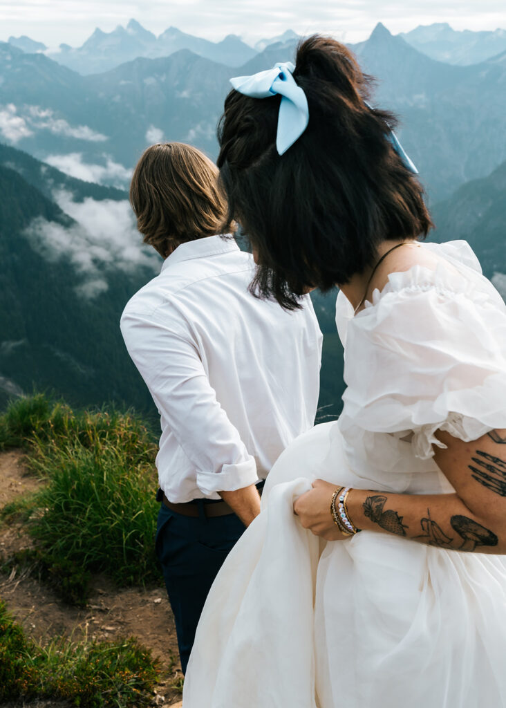 a groom leads his bride down a mountain trail during their north cascades elopement