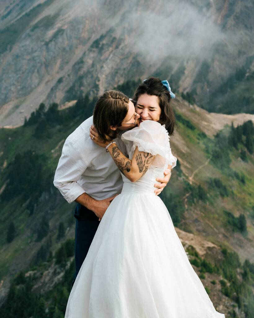 a groom kisses his bride as she smiles during their north cascades elopement