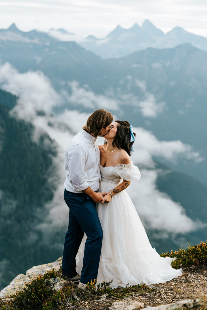 a couple embrace and share a celebratory kiss in front of beautiful mountains during their north cascades elopement 