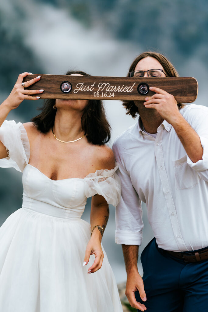 a couple in their wedding attire share a shot ski inscribed with the words "just married" and their north cascades elopement date