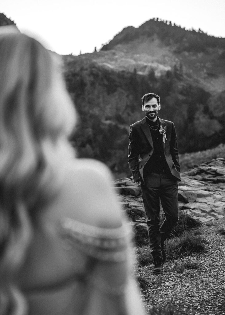 shot from over the shoulder of a bride, we see her perspective of how she sees her groom. he smiles sweetly at her as he walks towards her during their north cascades elopement