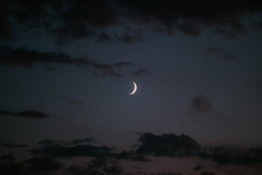 a shot of a beautiful crescent moon in a dusky cloudy sky 