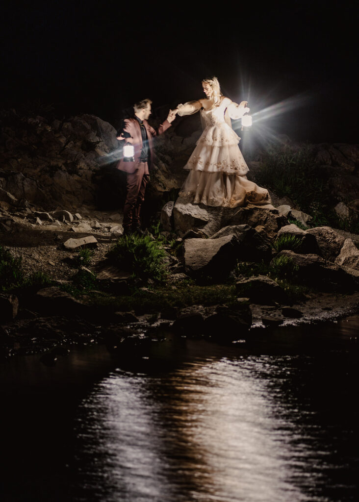 an image of a bride and groom holding lanterns exploring a mountain tarn during their north cascades elopement