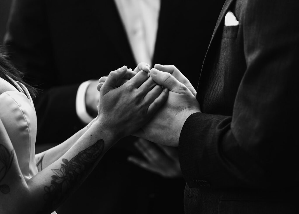 a black and white horizontal  image of a couple clasping hands 