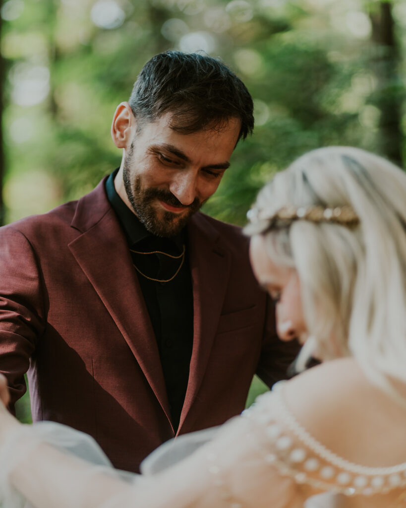 a groom gazes lovingly at his bride during their first look. he smiles in awe of her wedding attire for their mount baker elopement