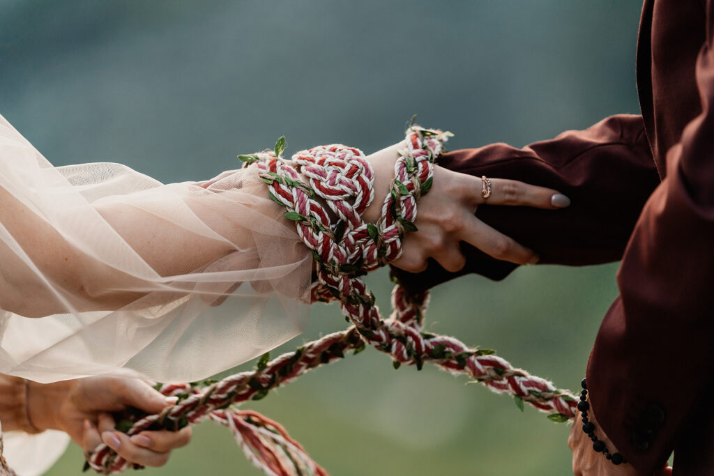 during their mount baker elopement, a couple uses a magenta and white gold Celtic hand fasting knot during their elopement ceremony