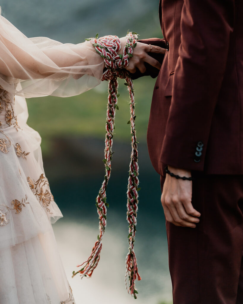 during their mount baker elopement, a couple uses a magenta and white gold Celtic hand fasting knot during their elopement ceremony