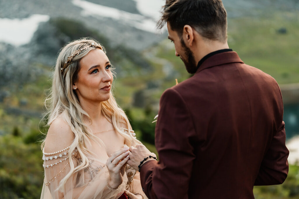 a shot focused on the brides faces as she gazes lovingly at her groom as she carefully places his wedding ring on his finger during their mount baker elopement