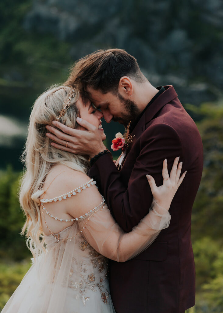 in their wedding attire, a bride and groom embrace and press their faces together during their mount baker elopement