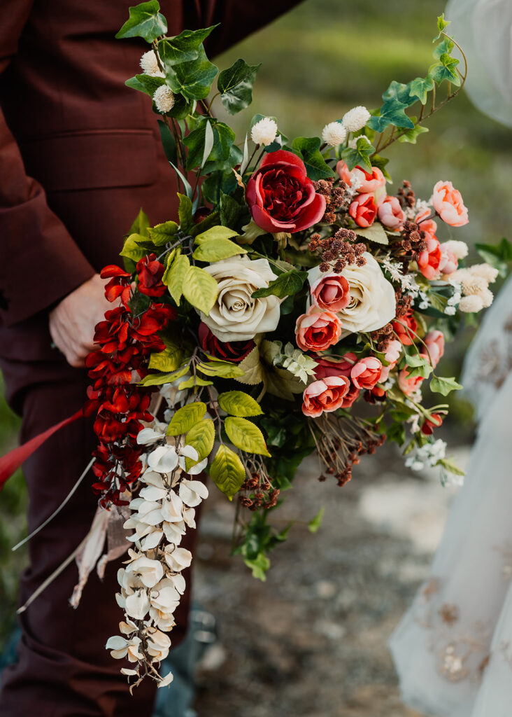 a close up shot of a beautiful cascading bouquet made with rose, red, and white silk florals  