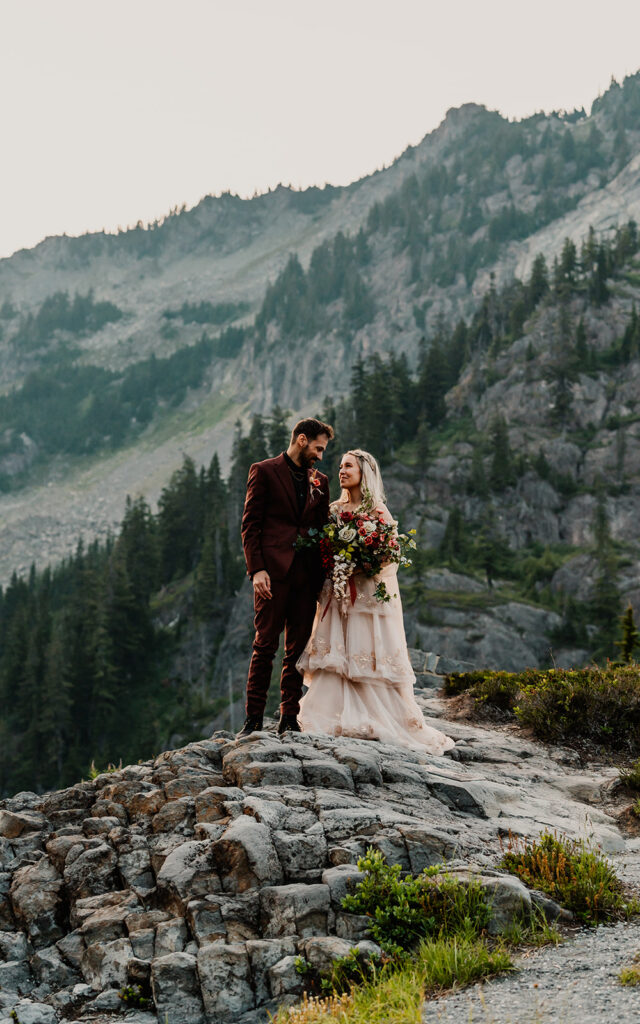 a bride and groom in wedding attire gaze at each other with a stunning mountain backdrop behind them during their mount baker elopement