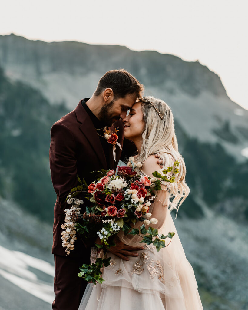 a bride and groom press their foreheads together sweetly while she holds her bouquet 