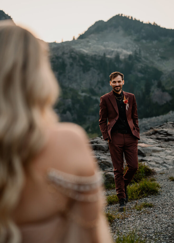 shot from over the shoulder of our bride, focusing on her groom as he walks towards her, smiling sweetly during their mount baker elopement