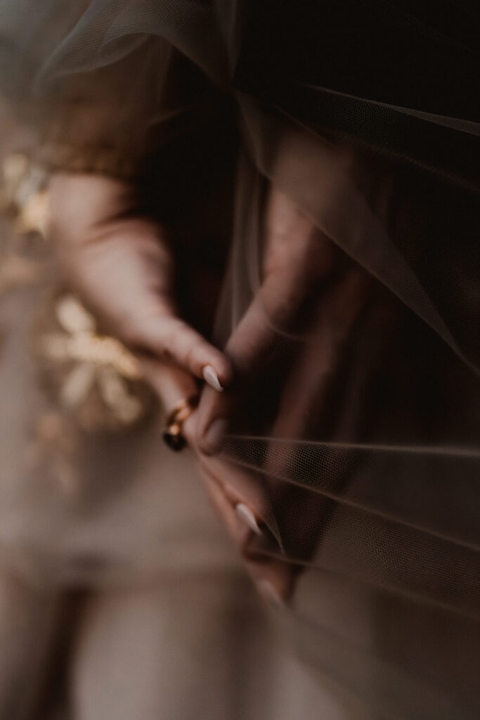 a close up shot of hands pressing towards each other and connecting through the gauzy fabric of the brides dress during their mount baker elopement 