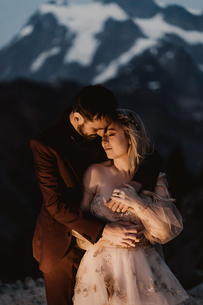 an image taken at twilight of a couple in their wedding attire, illuminated by the light of a lantern during their mount baker elopement