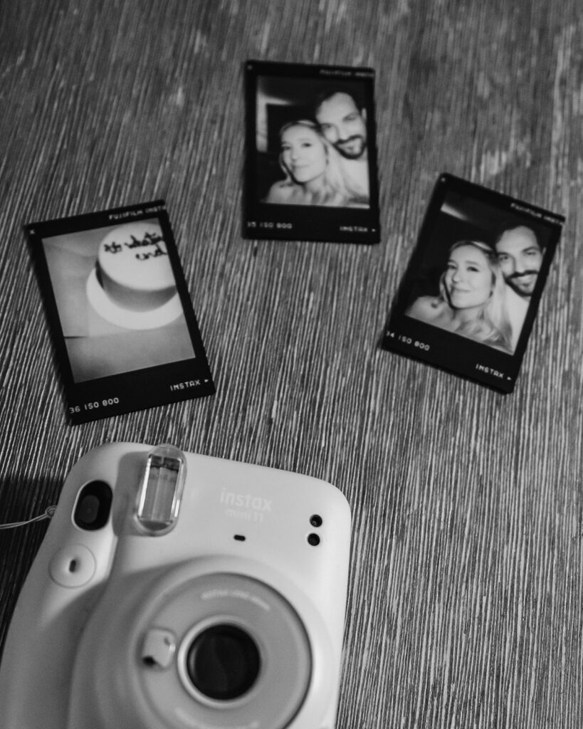 a casual, candid shot of black and white polaroids from throughout the day of this mount baker elopement strewn on a wooden table