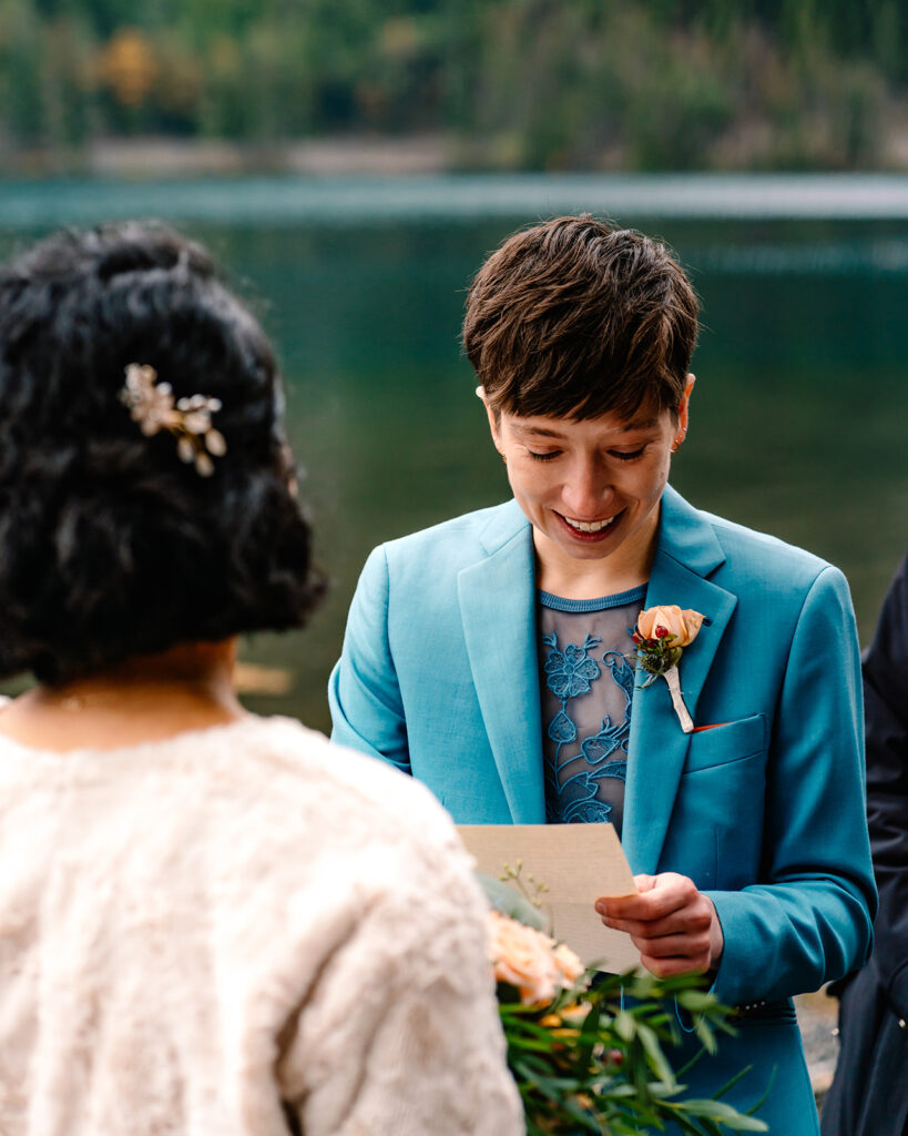 a bride smiles and softly cries as she reads her vows during her lake crescent elopement 