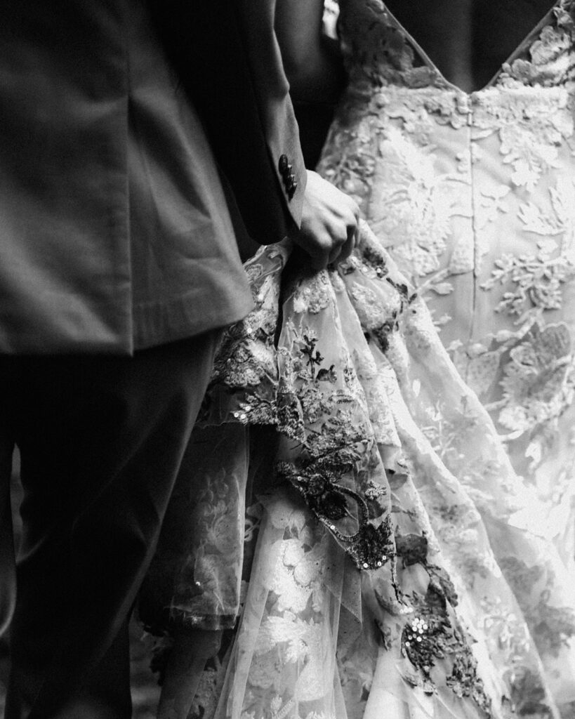 a black and white image of a wedding dress. It's held by the partner and is caked with dirt from the adventures of the day.