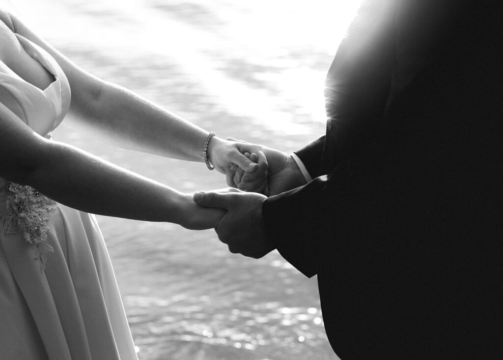 a black and white detail shot focused on the hands of a bride and groom embracing during their lake crescent wedding