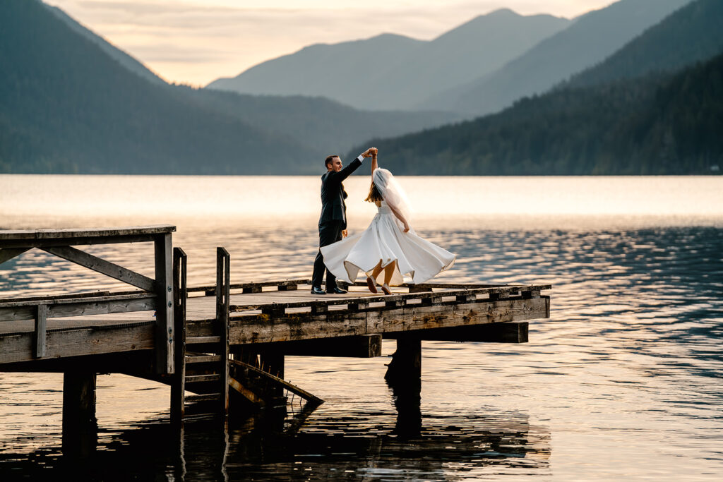 a bride and groom share a first dance at the edge of a dock overlooking lake crescent 