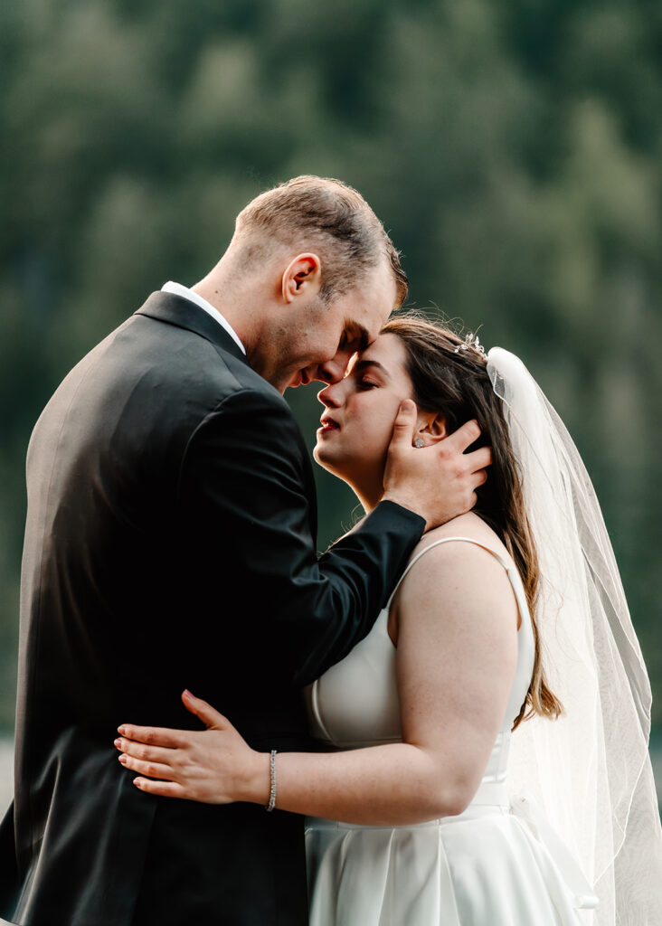 a bride and groom embrace, pressing their foreheads together during their lake crescent wedding 
